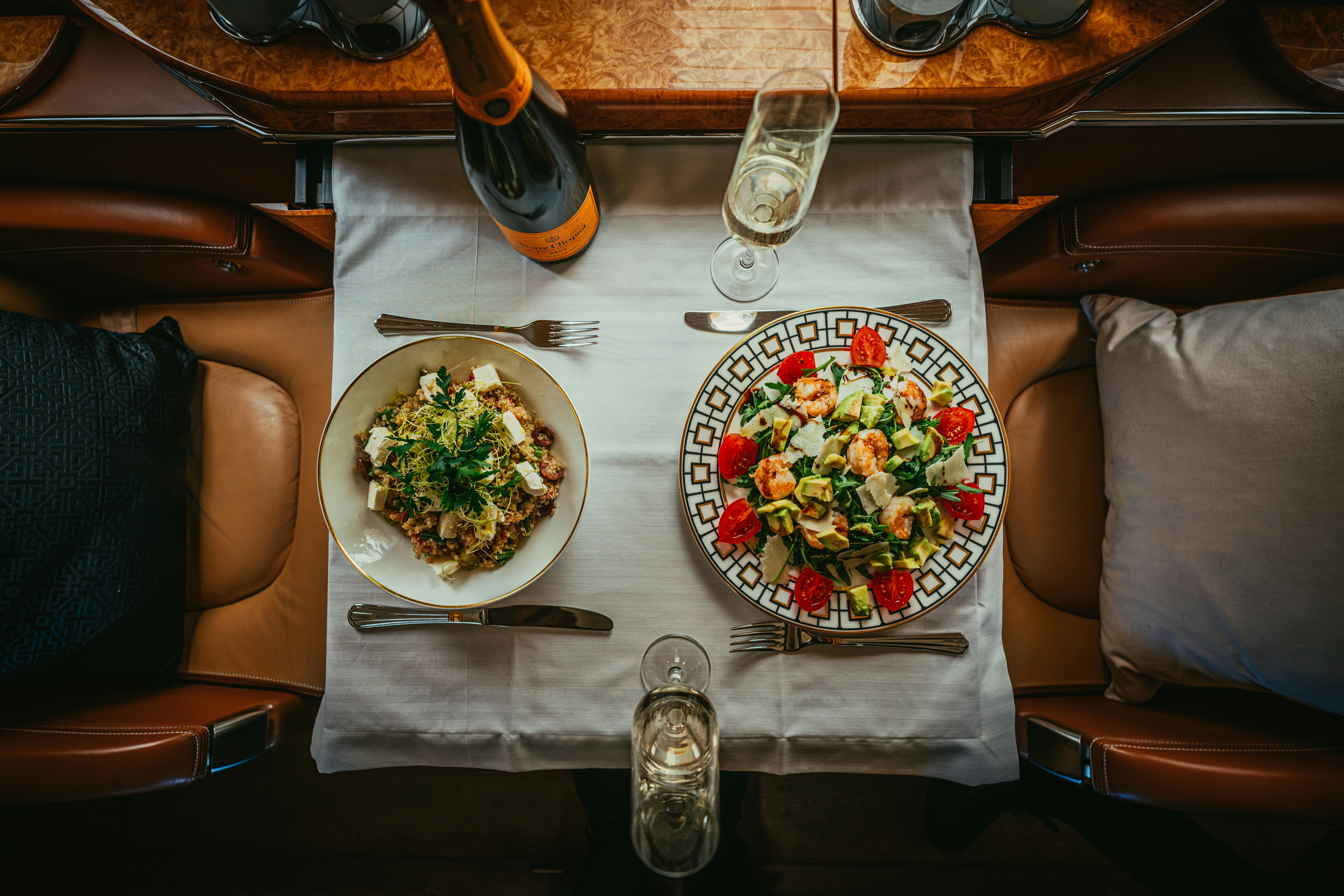 Gourmet shrimp and quinoa salads served with champagne on a luxury private jet table.